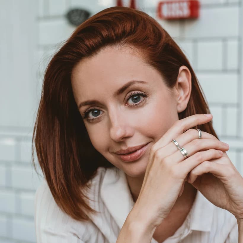 A woman with auburn hair resting her chin on her hand
